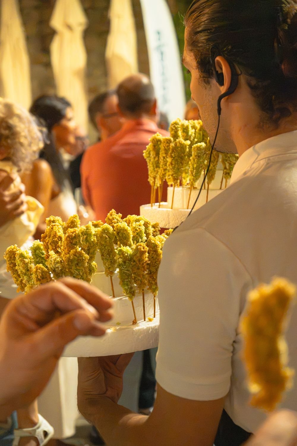 Camarero pasando una bandeja de brochetas entre los invitados