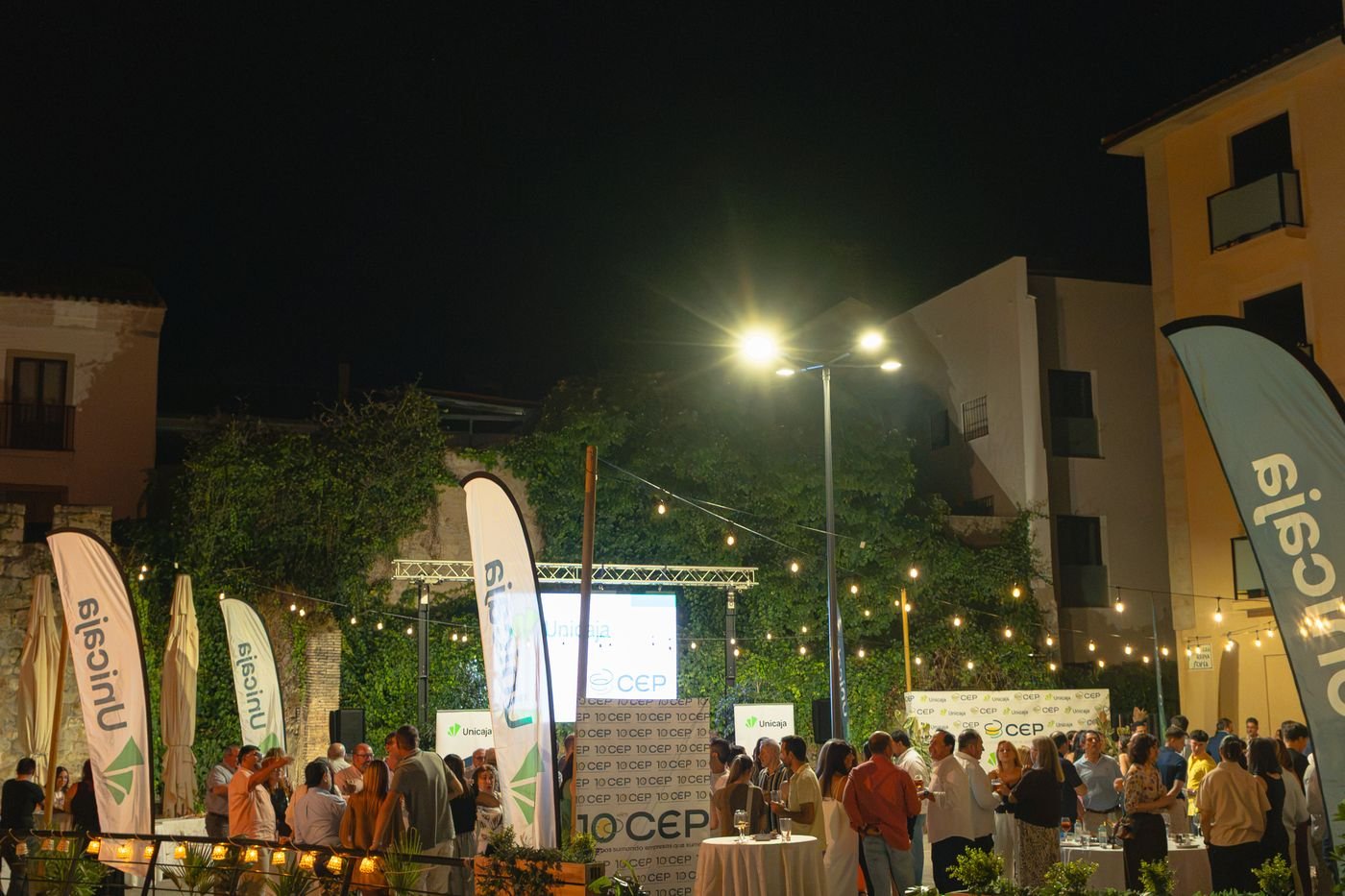 El evento de noche, con iluminación y mesas altas en el exterior
